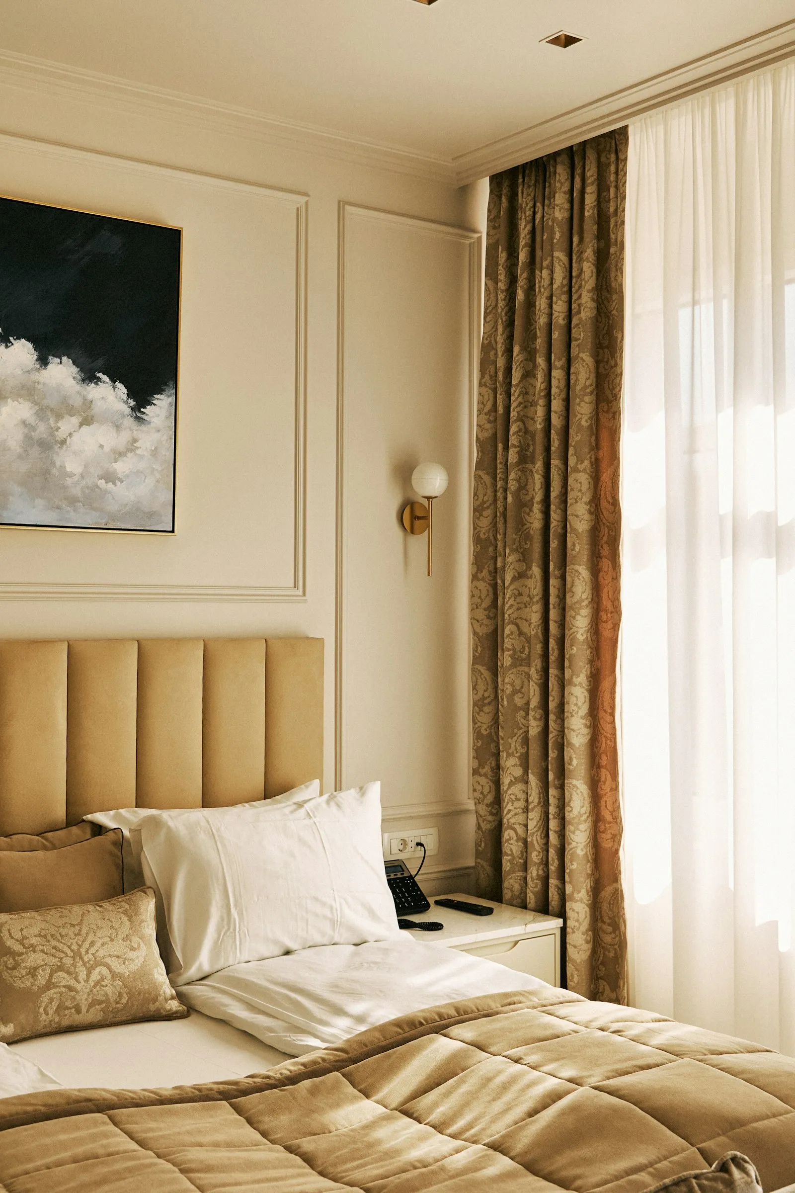 Camera elegante con letto matrimoniale, testiera imbottita e tende chiare