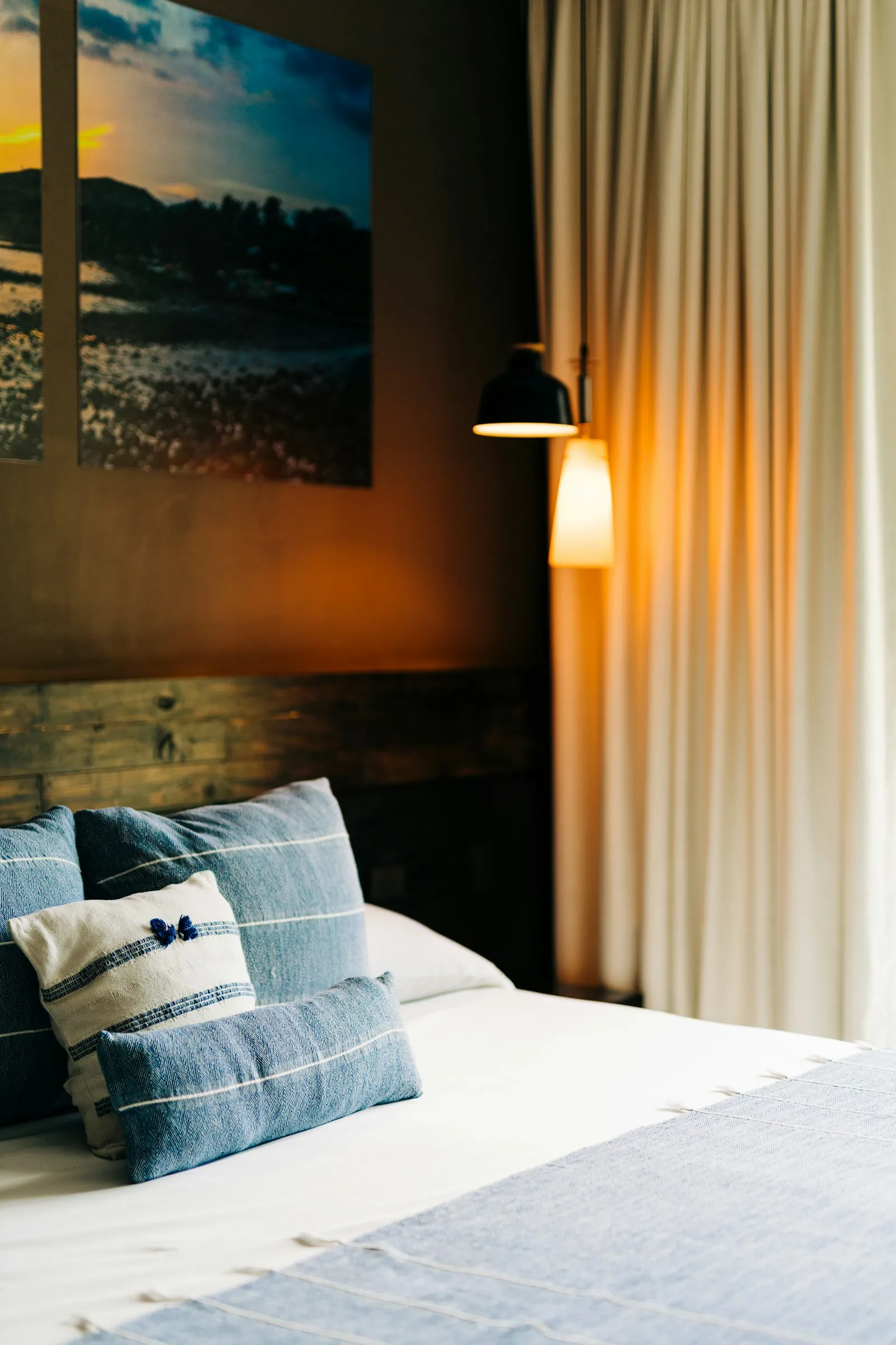 Camera raccolta con letto, cuscini blu e luce calda da una lampada a muro