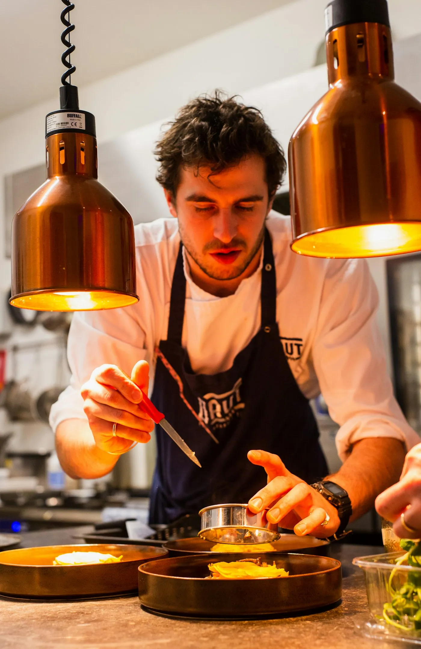 Lo chef impiatta sotto le lampade della cucina