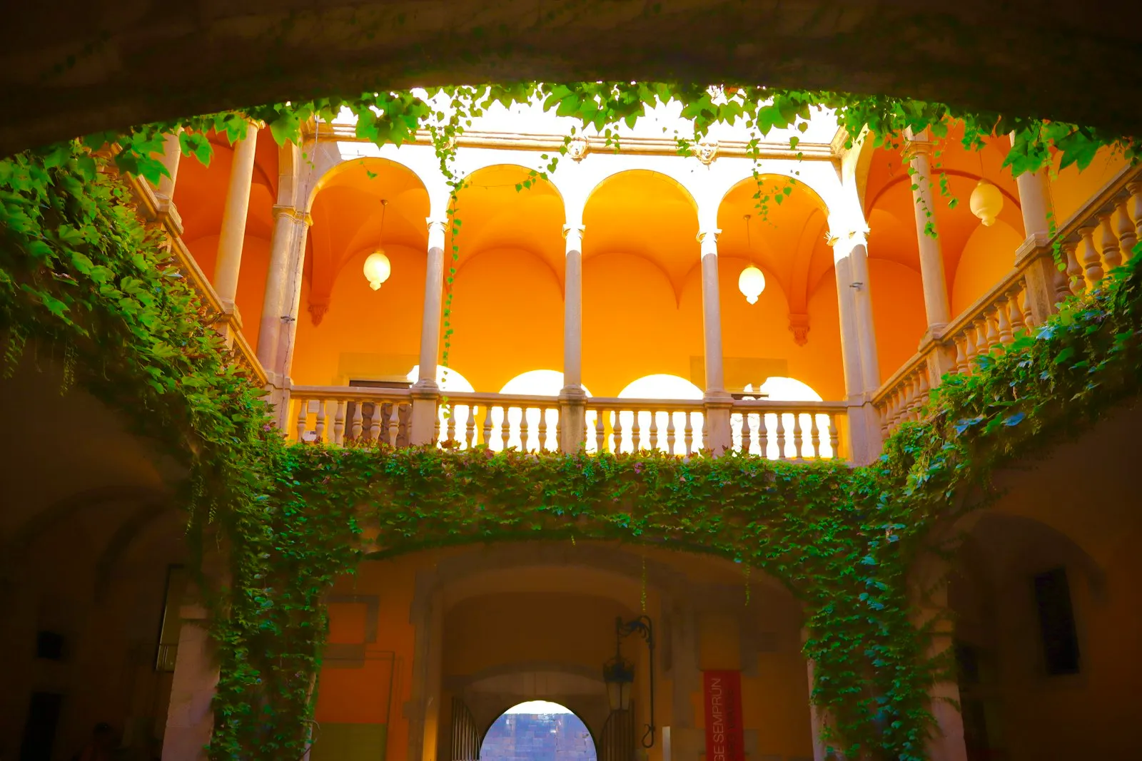 Cortile ad archi con muri gialli e colonne coperte d’edera