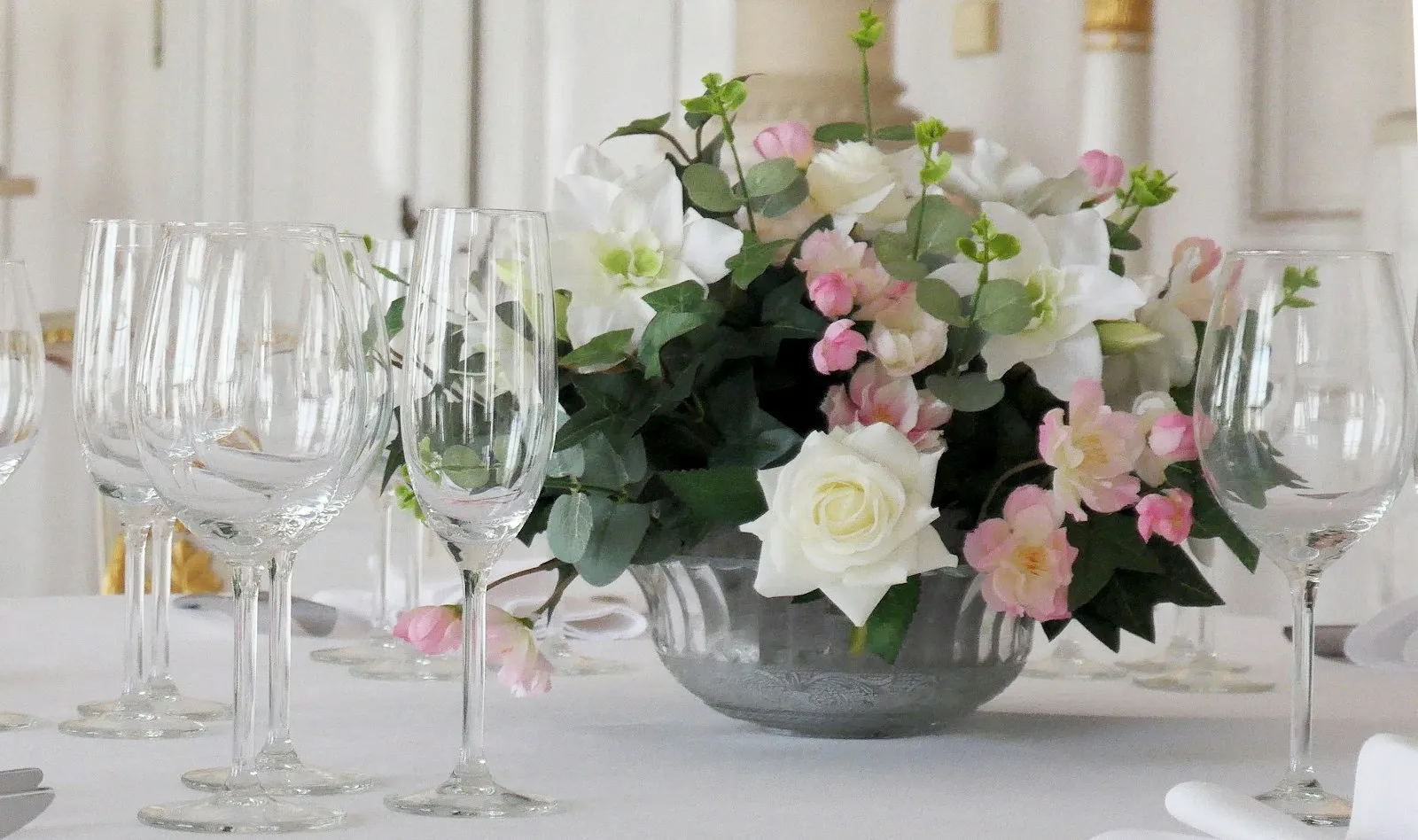 Centrotavola di rose bianche e rosa tra bicchieri di cristallo