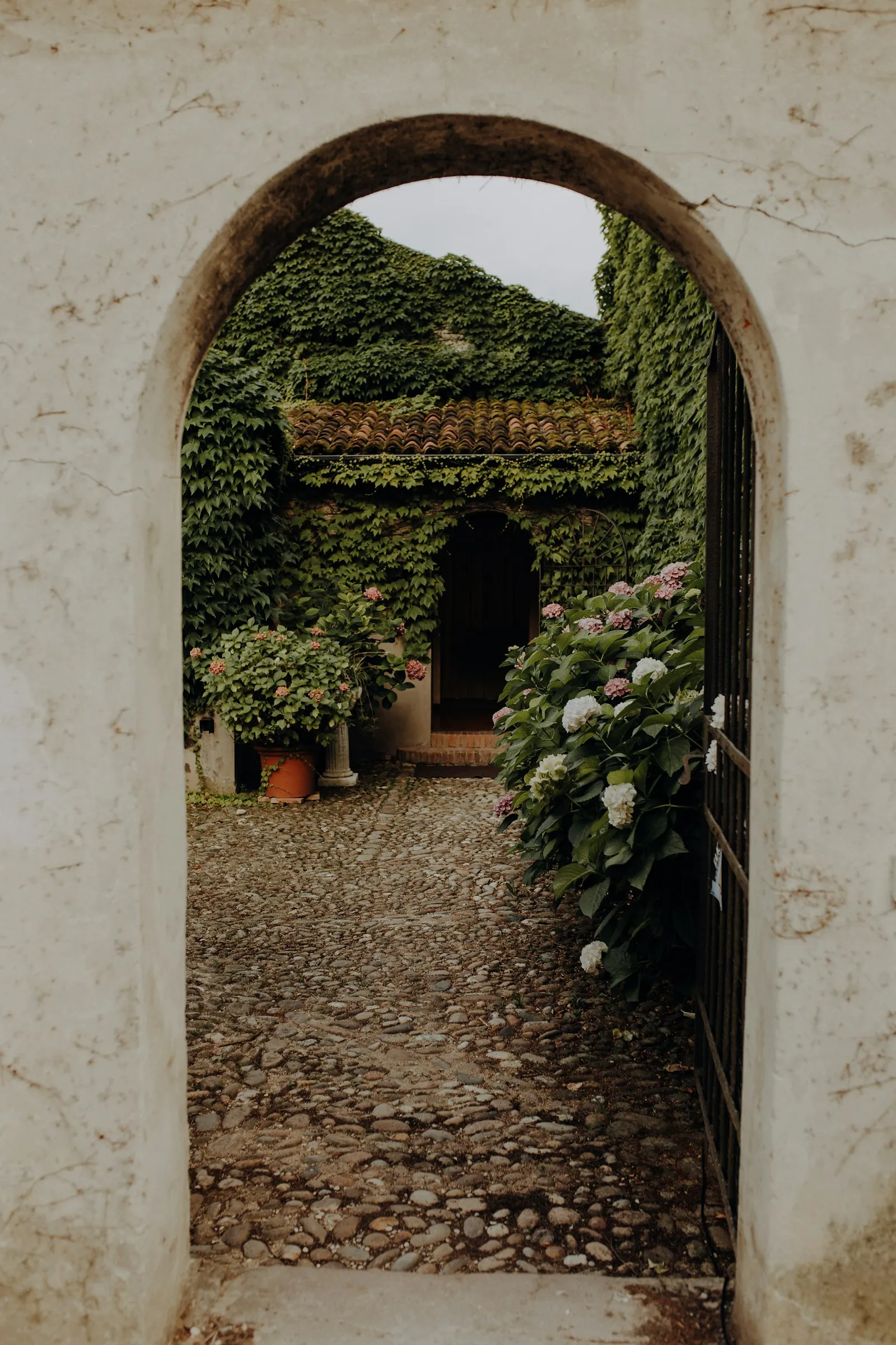 Vialetto in pietra con cancello ad arco e ortensie