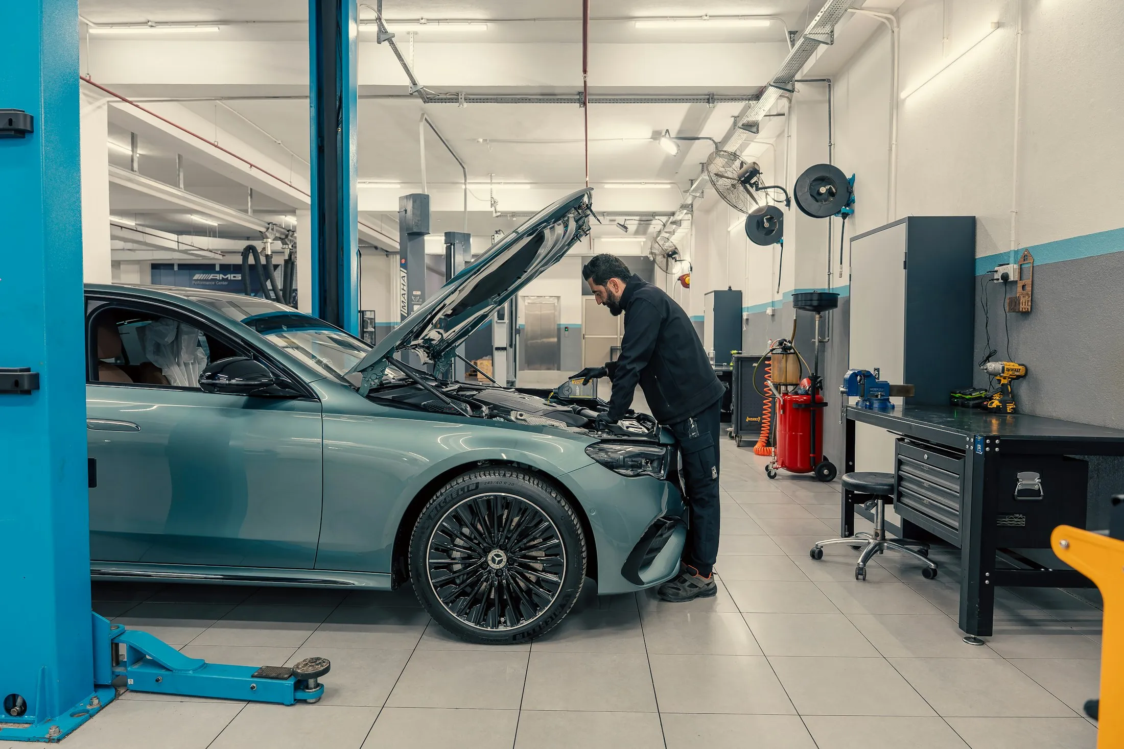 Un meccanico al lavoro su un’auto con il cofano aperto, in un’officina luminosa
