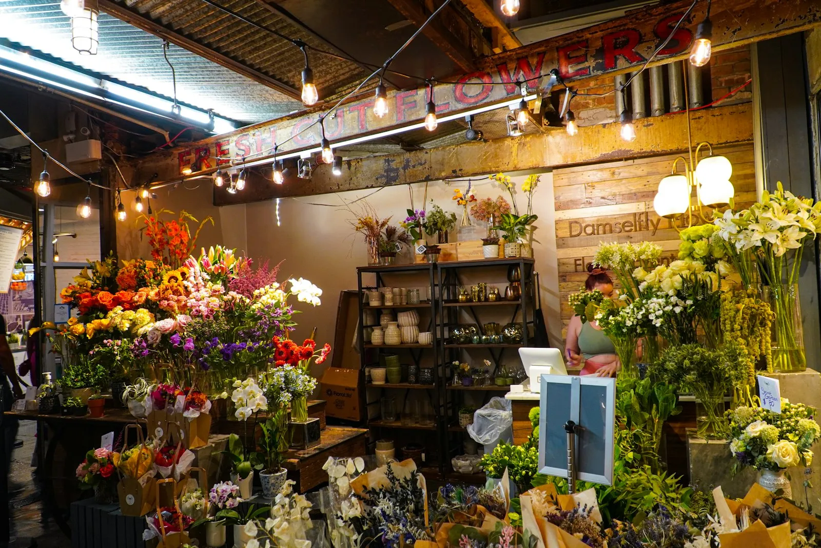 Interno della fioreria pieno di fiori e piante sotto le luci