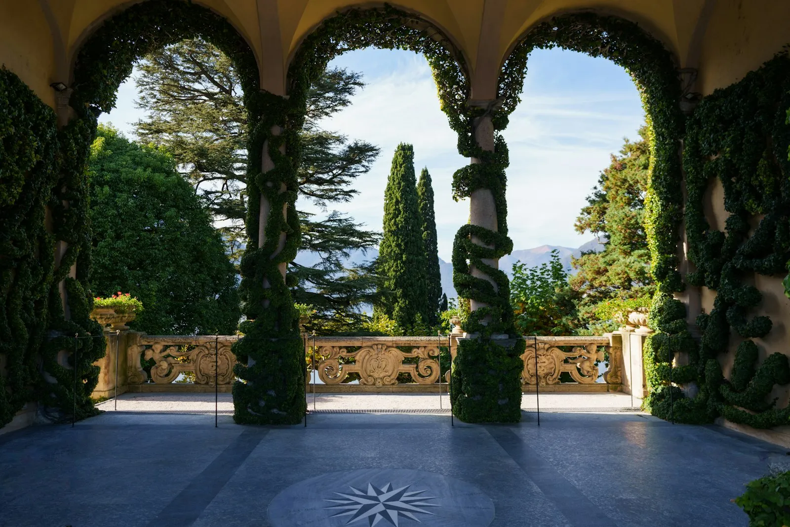 Arcate in pietra coperte di verde con vista sul lago