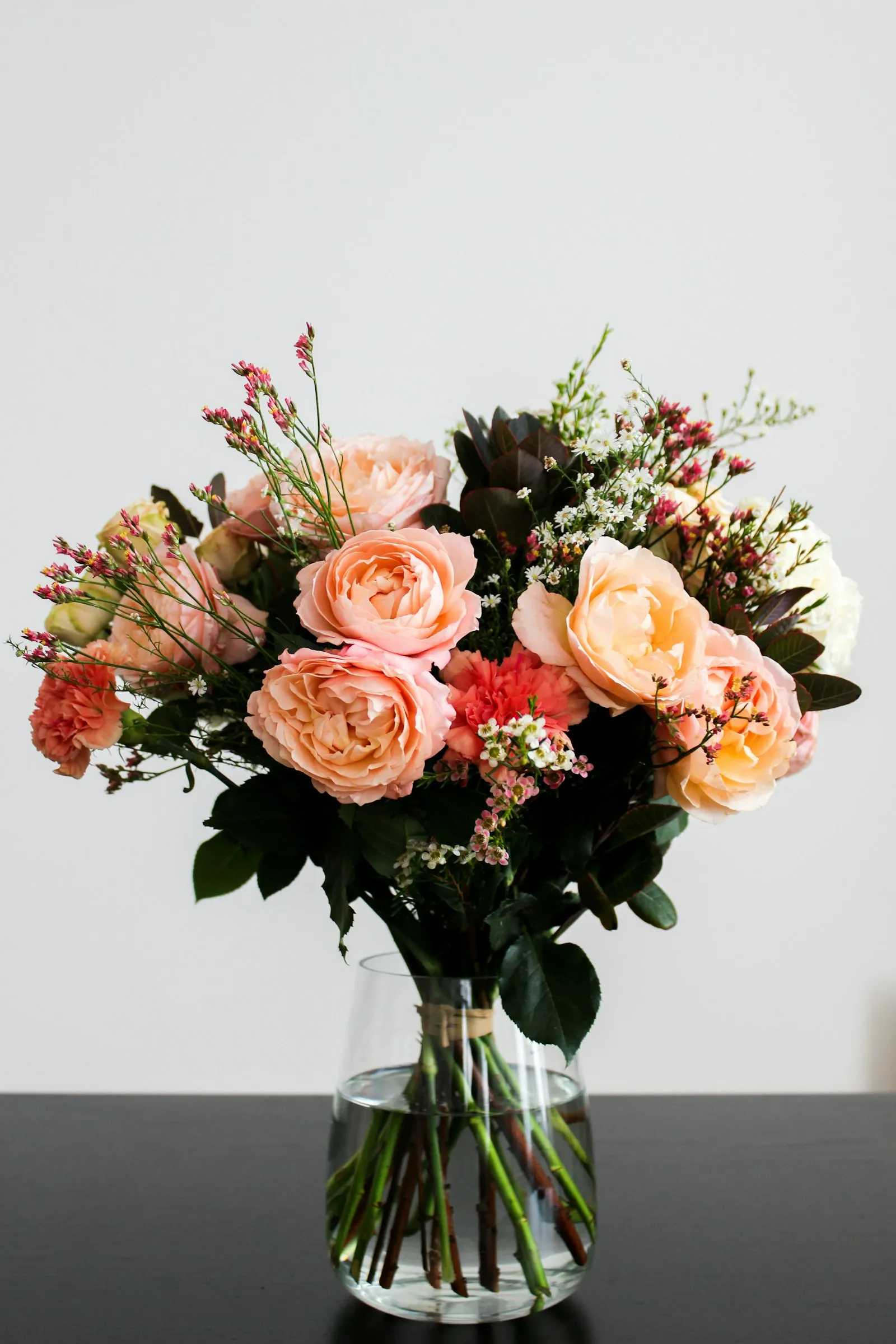 Bouquet di rose pesca e rosse in un vaso di vetro