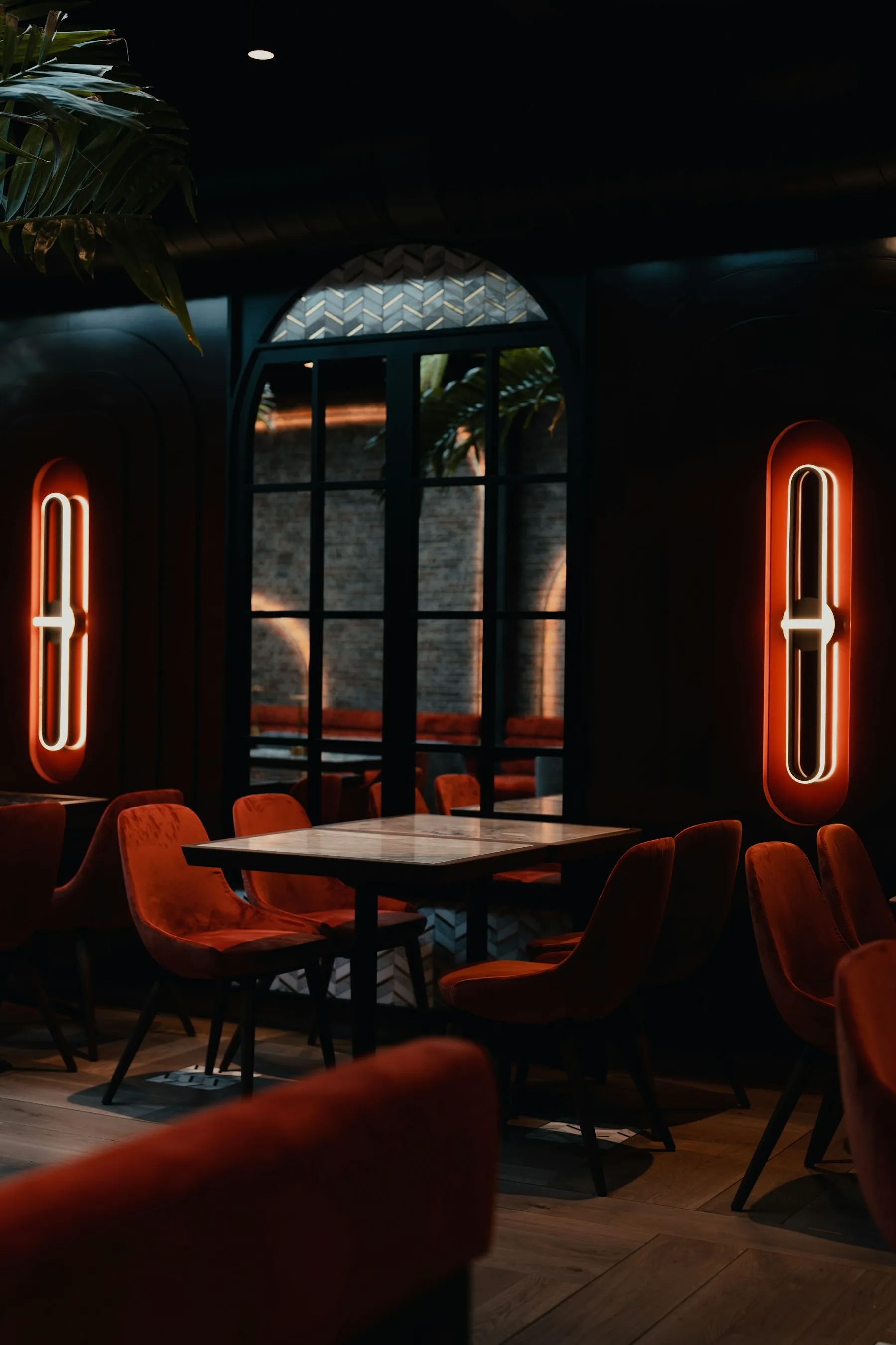 Sala con sedute arancioni, tavolo rotondo e luci al neon